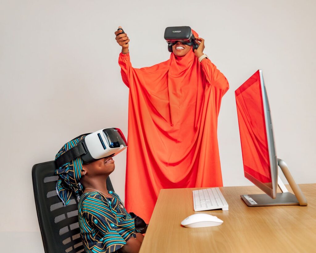 pexels photo 16385068 16385068 Two women enjoying VR technology indoors, combining traditional attire with modern virtual experiences.