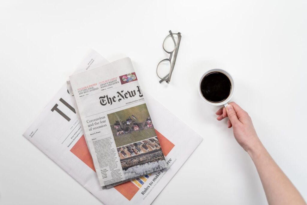 pexels photo 3944417 3944417 Top view of a coffee cup, newspapers, and eyeglasses on a clean white desk, ideal for a morning routine theme.